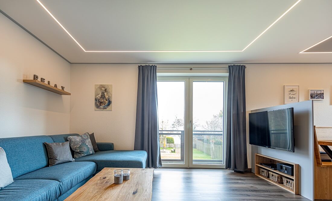 Plameco Spanndecke: Wohnzimmer mit mittigem LED-Stripe, der hinter der Spanndecke verborgen ist